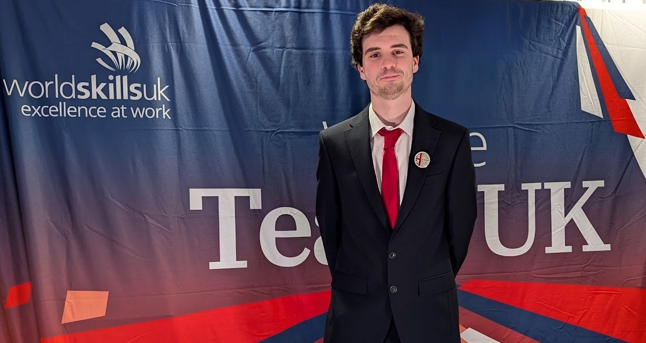 Oscar McNaughton standing in front of WorldSkills banner