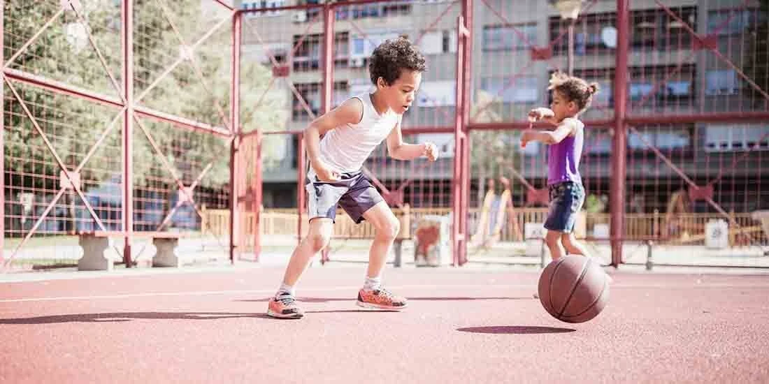 Young children playing basketball on an city playground