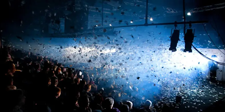 Confetti blowing around lights in a dark room.