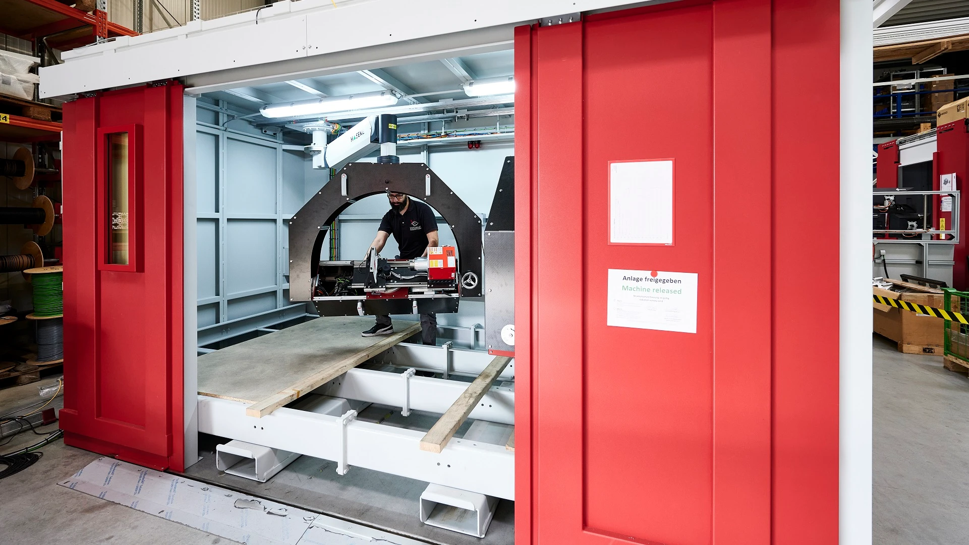 A worker adjusts X-ray equipment inside a large protective X-ray cabin.