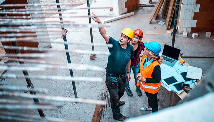 three construction workers on a jobsite pointing and looking at a structure