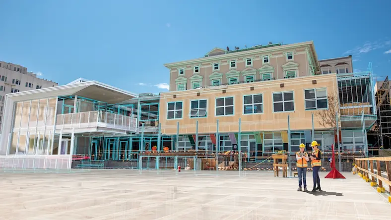 Construction workers stand in front of a building with a digital overlay