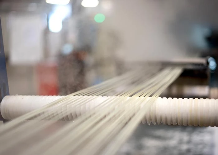 Plastic strands emerge from an extrusion machine