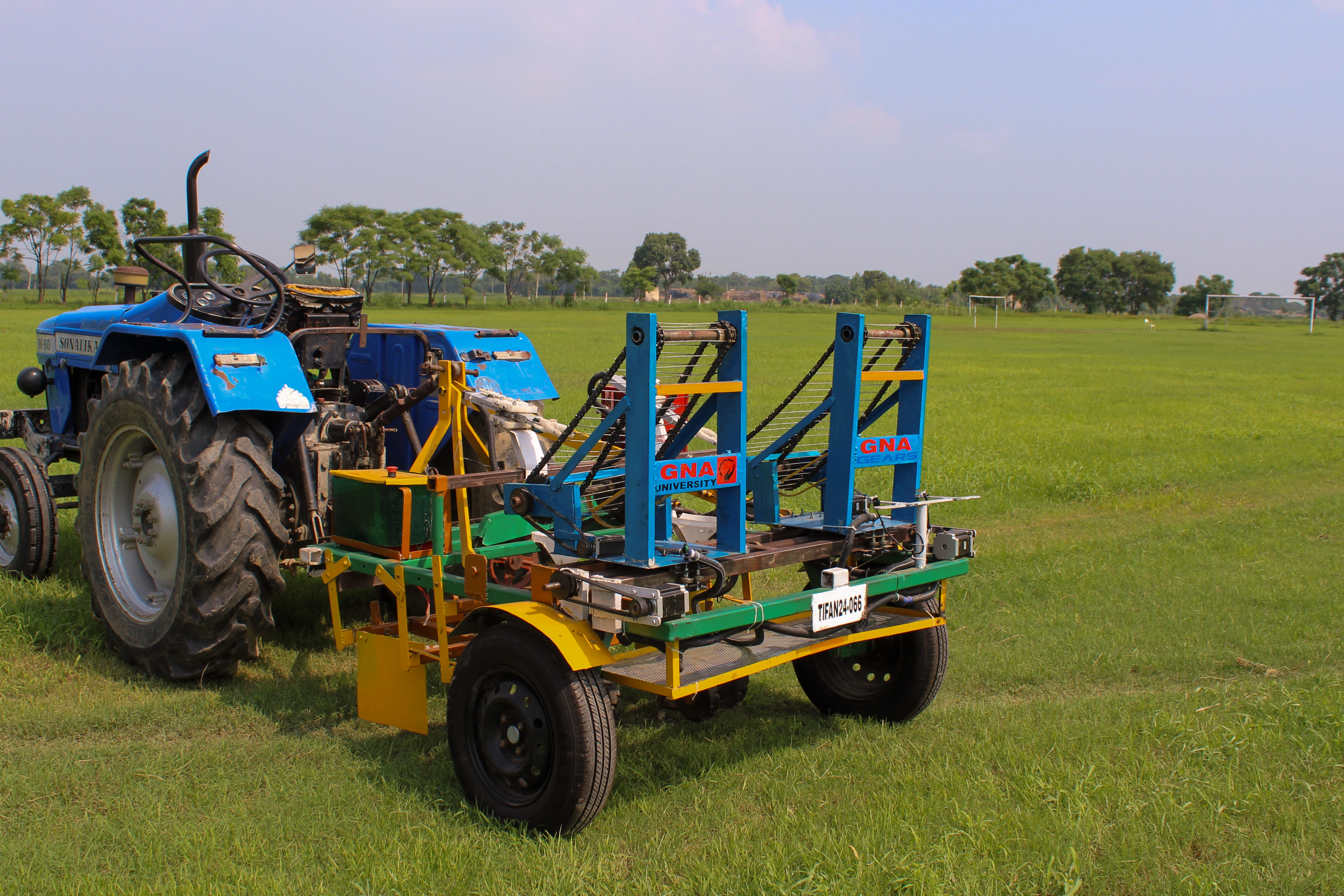 Automated multi-vegetable transplanter hooked to tractor in field