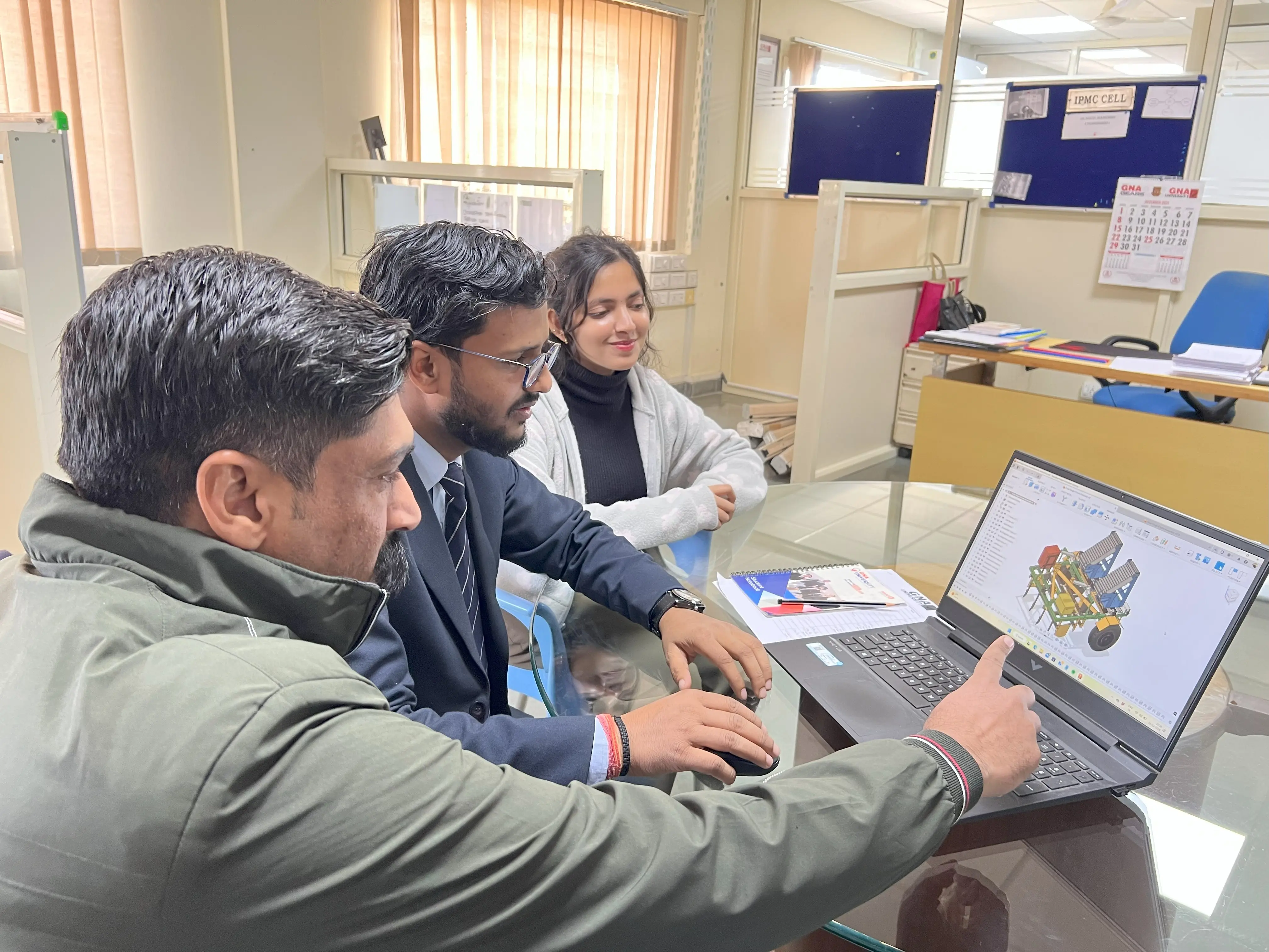Professor and students looking at laptop with Automated Multi-Vegetable Transplanter design in Autodesk Fusion