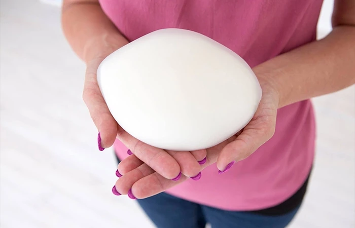 Woman holds manufactured breast prosthesis