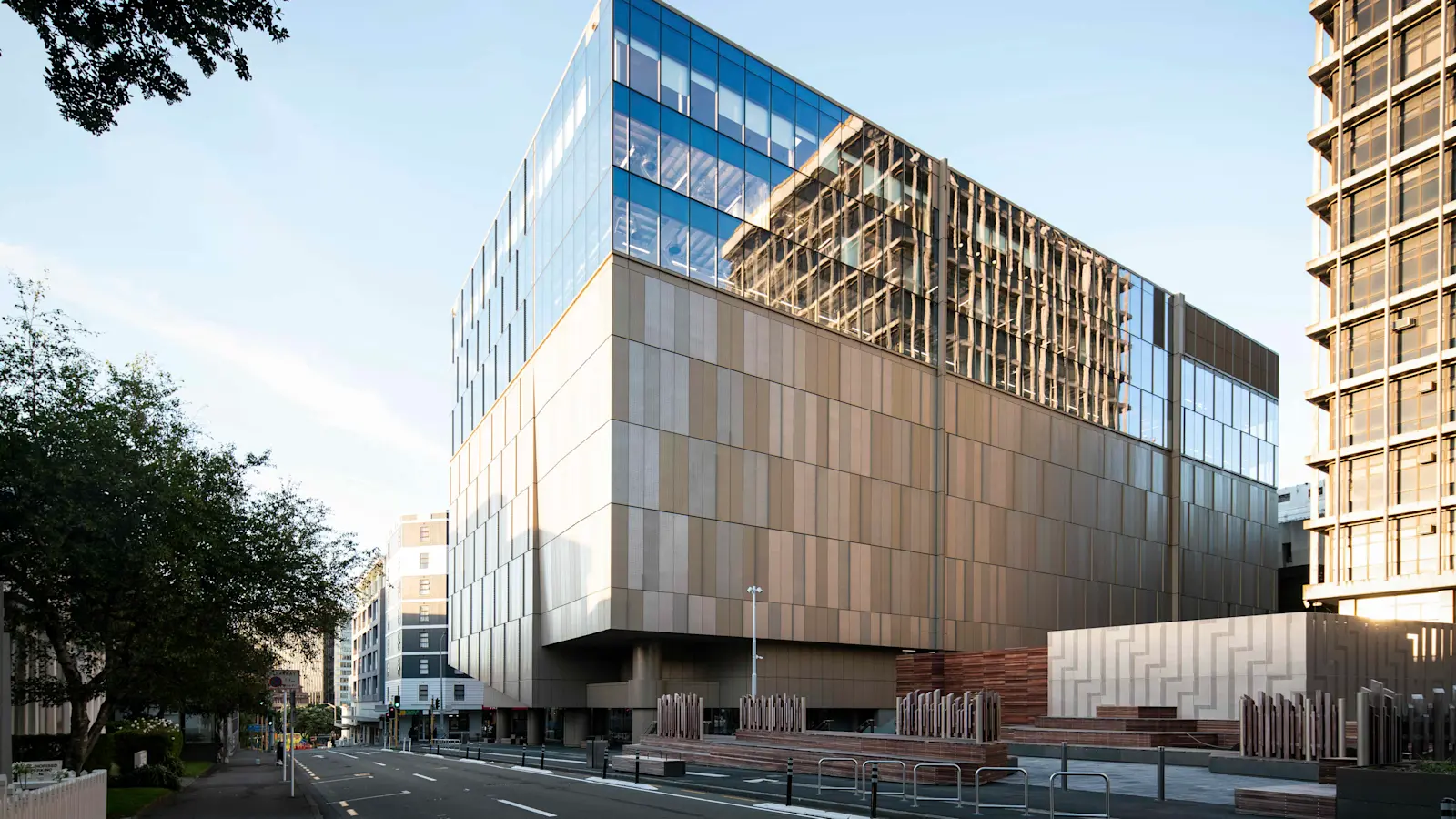 Modern high-rise building surrounded by other skyscrapers and residential structures in an urban cityscape.