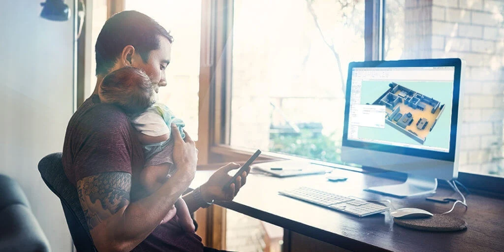 a man holds his baby while he works.