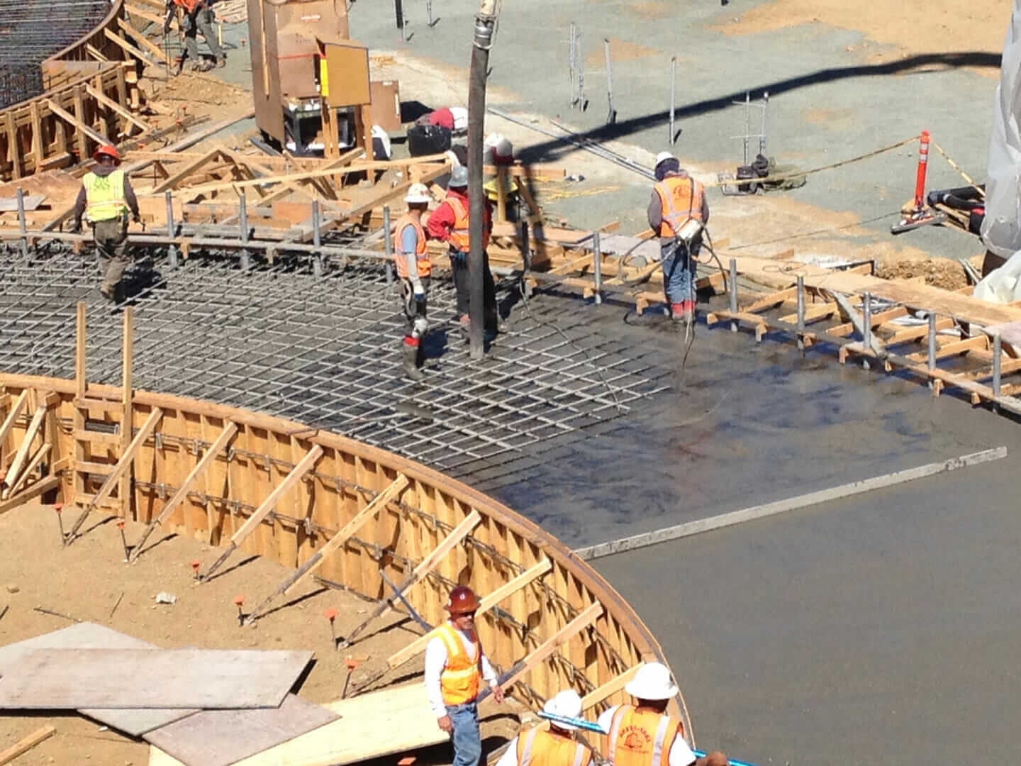 Construction workers pour cement into a form structured with rebar.
