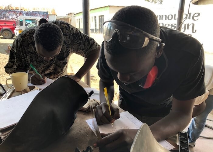 Apprentices work on motorcycle ambulance design