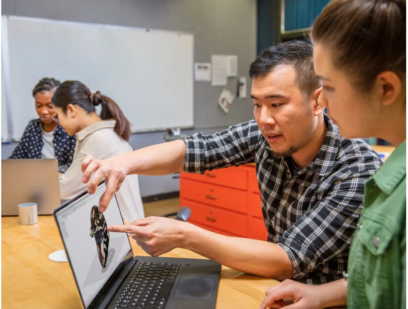 educator and student look at a laptop intently