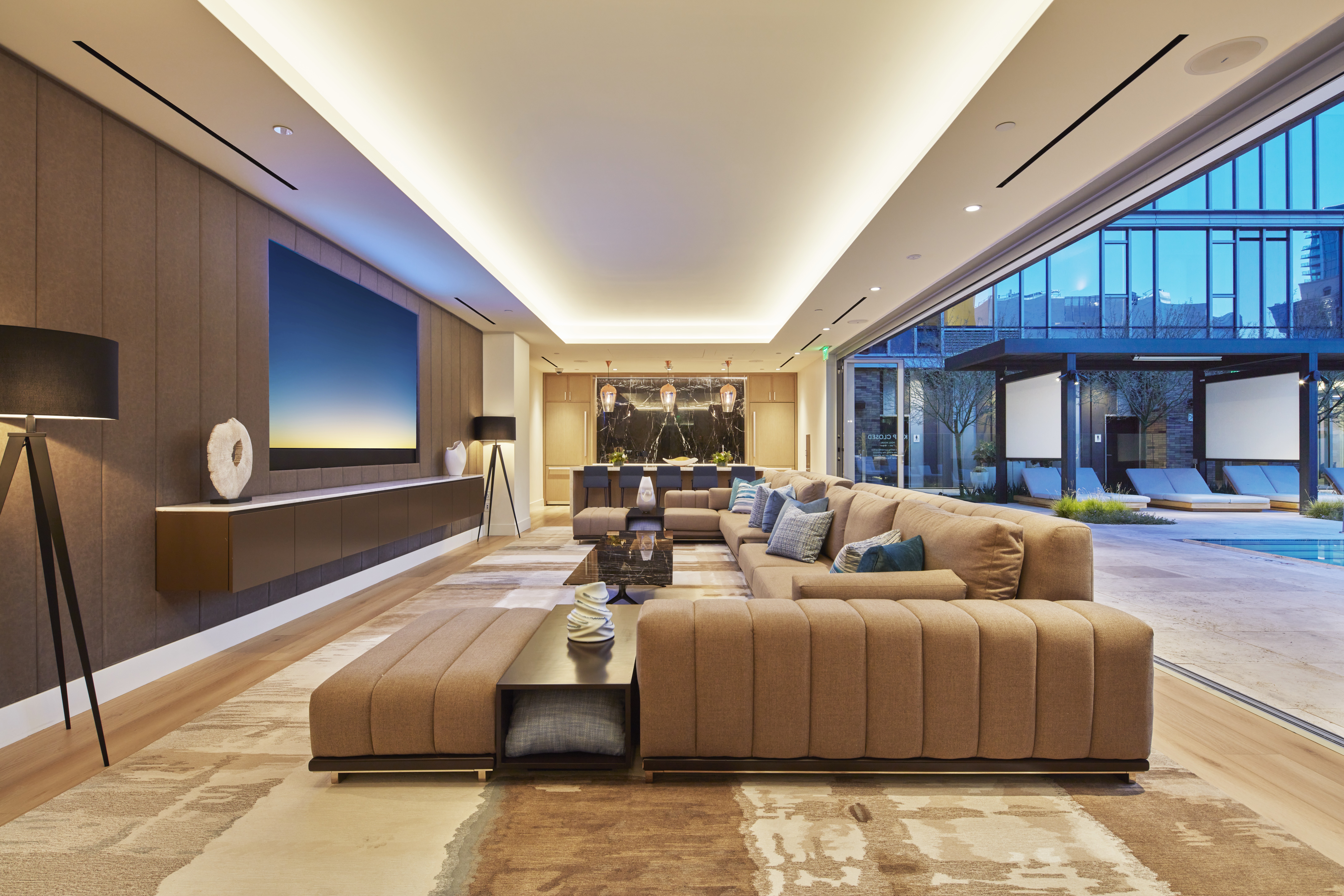 Large sectional sofa with flat screen TV and open doors to pool