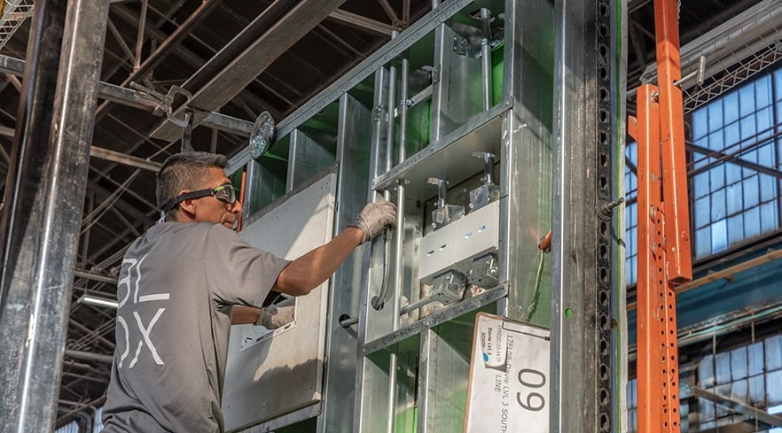 Workers assemble standardized components in a manufacturing process.