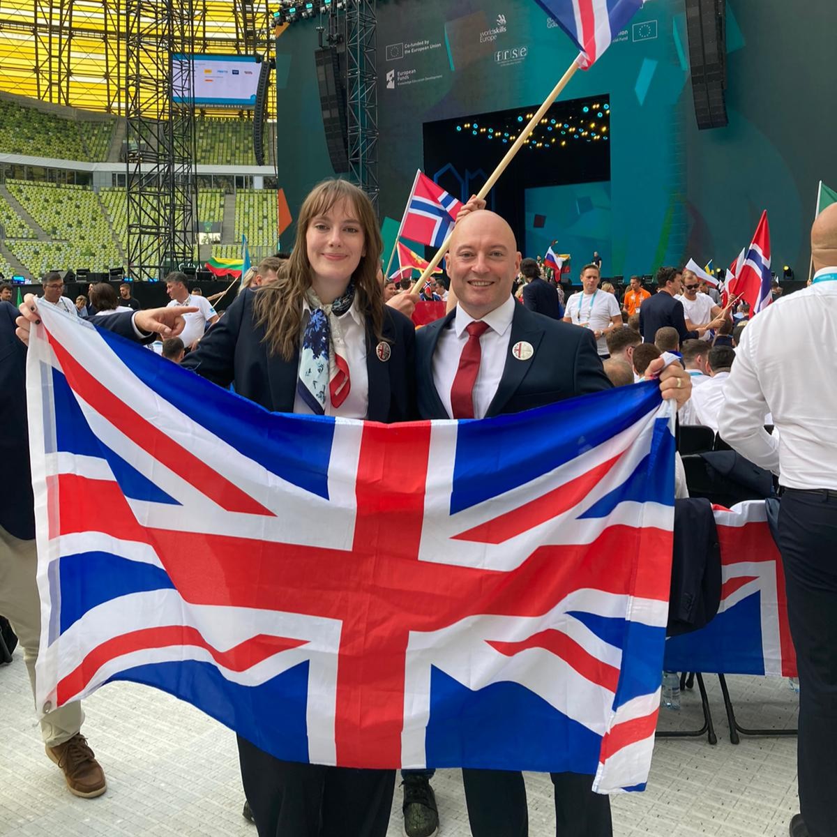 Isabelle Barron and Michael McGuire hold UK flag at EuroSkills 2023