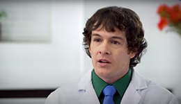 A man with a white coat, green shirt and a blue tie.