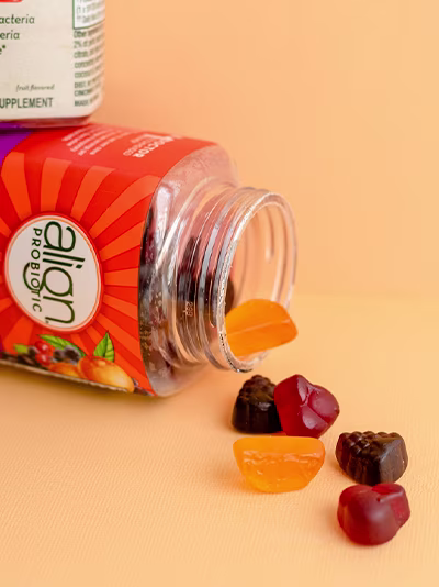 A bottle of Align DualBiotic Prebiotic+Probiotic gummies spilling out onto a surface.