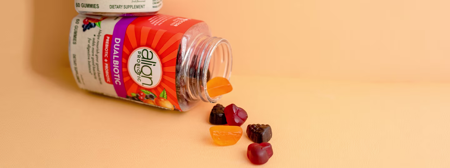 A bottle of Align DualBiotic Prebiotic+Probiotic gummies spilling out onto a surface.