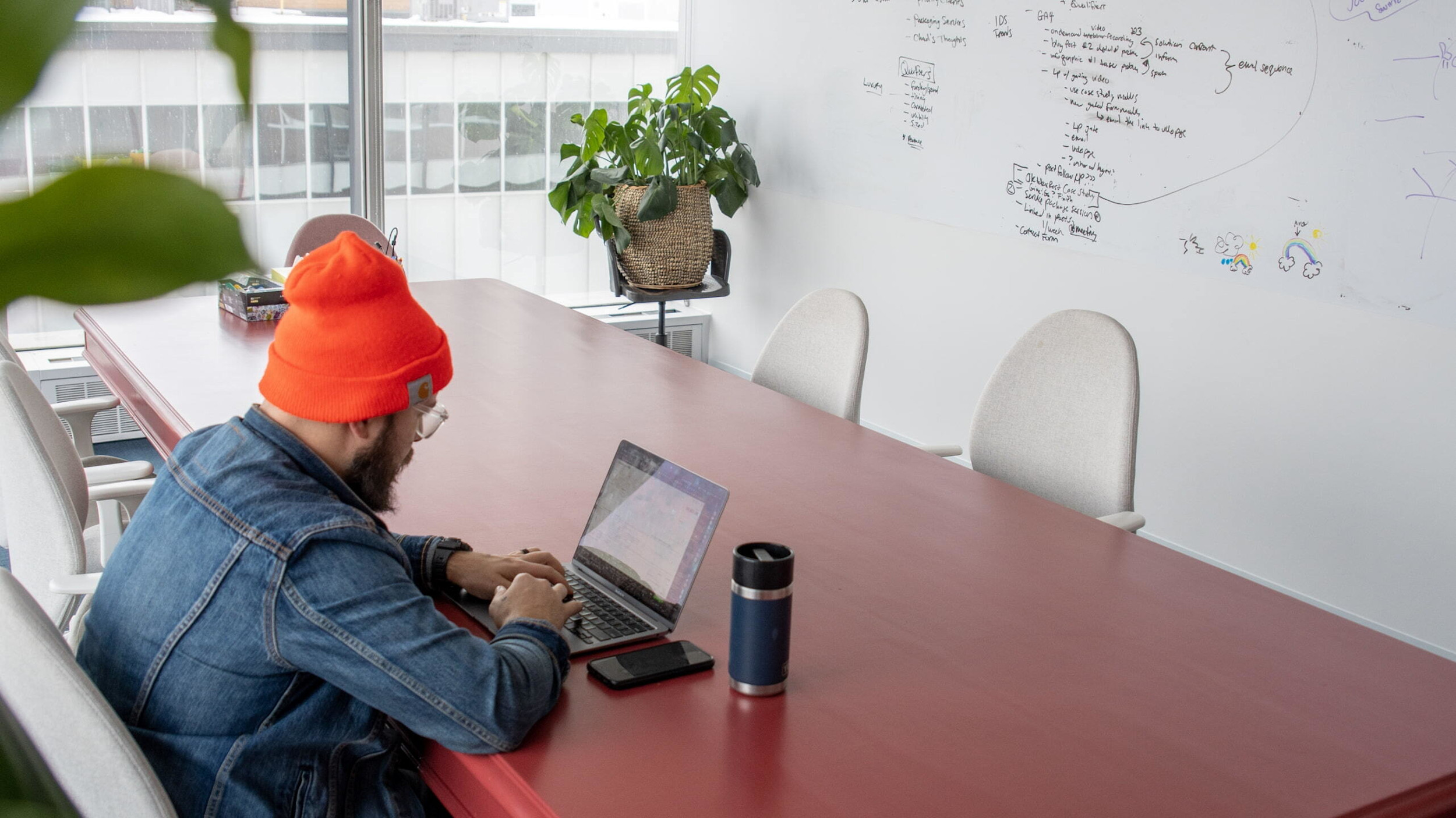 The company CEO sitting at a desk in the boardroom working on his laptop.