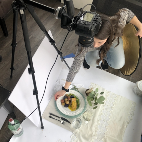 An overhead shot of a food photoshoot. There is a plate of colourful food setup on a tablecloth
