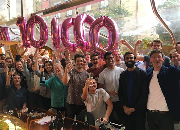 Team Bulb holding balloons in the shape of 100,000