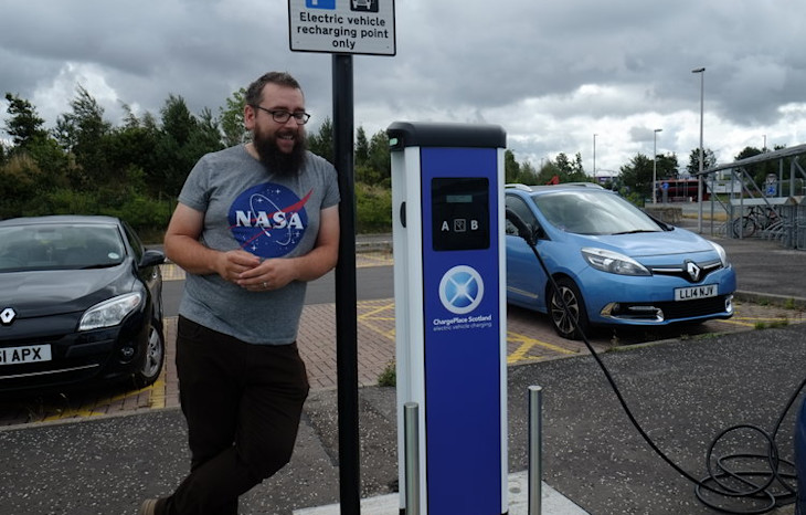 Man standing next to an electric charging station