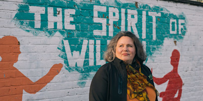 Debbie Mitchener standing in front of a wall with graffiti.