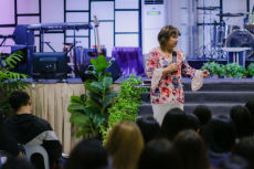 Cristina Sosso speaking on an elevated platform in front of the crowd at Christ Fellowship Church International (CCFI) in General Santos City.