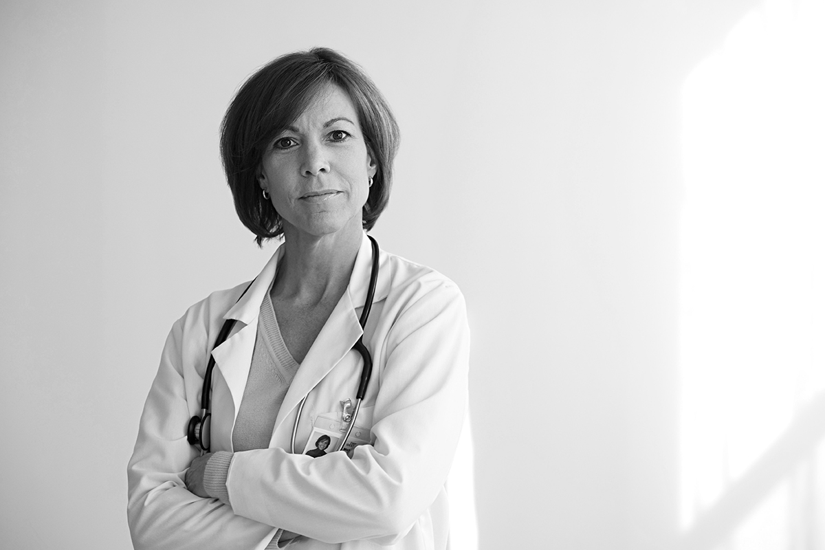 Black and white image of a female physician with arms crossed looking at the camera