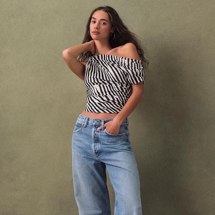 Woman poses in off-shoulder animal-print top paired with baggy light wash jeans.