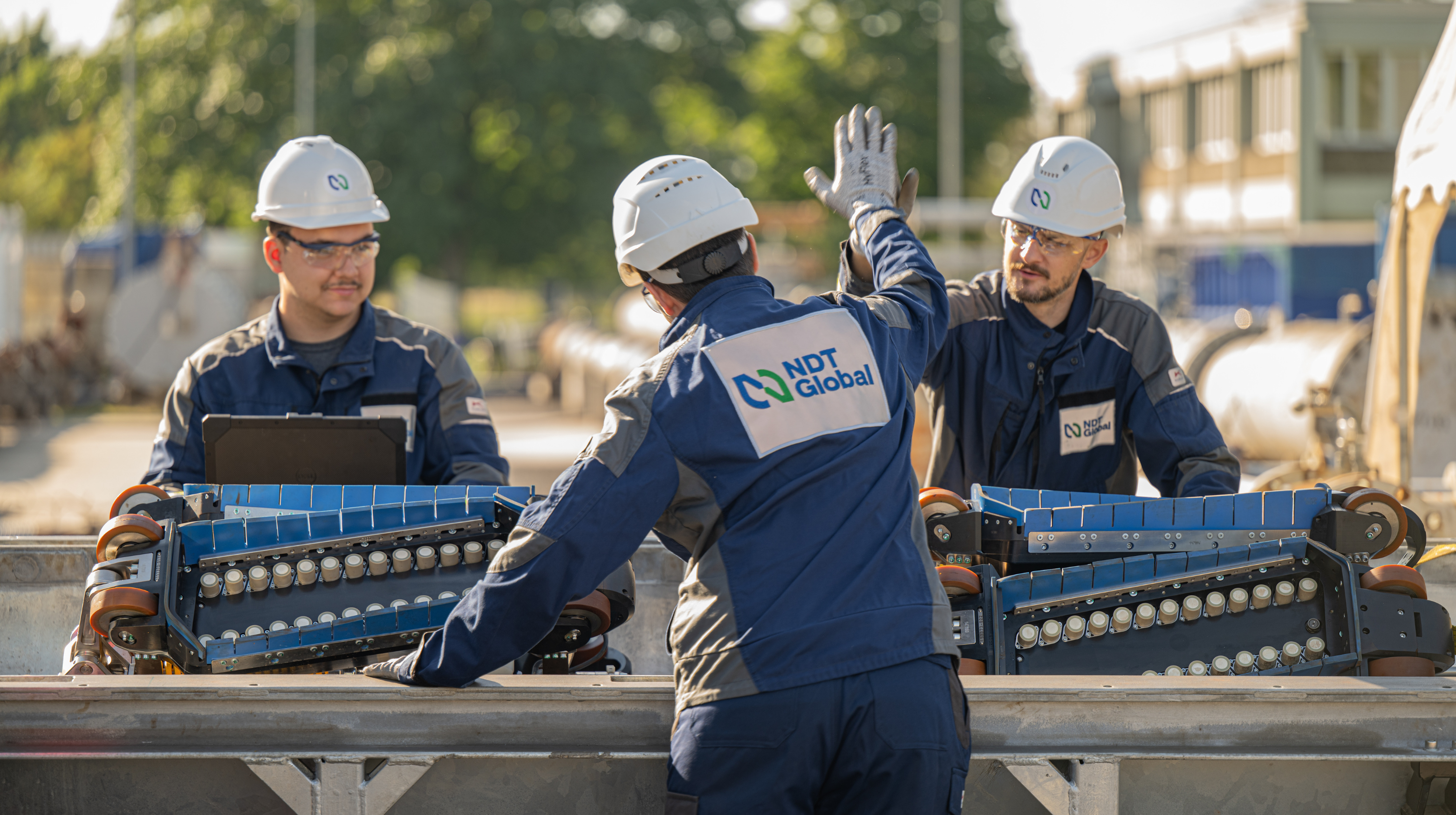 NDT Global Employees Standing and High-Fiving Around Inspection Tool