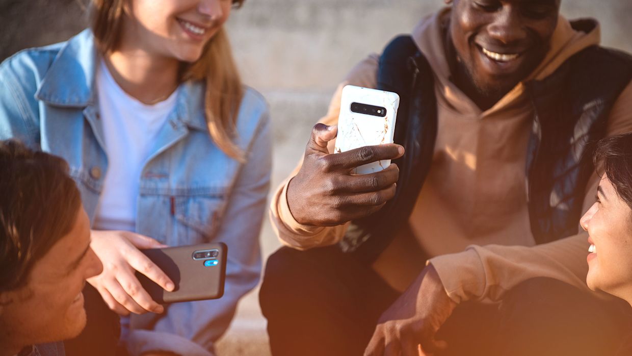 Fyra glada personer sitter i en trappa med sina mobiltelefoner.