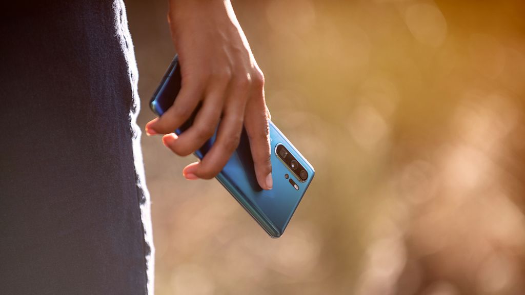 Mobiltelefon som hålls intill benet på en person som står upp.