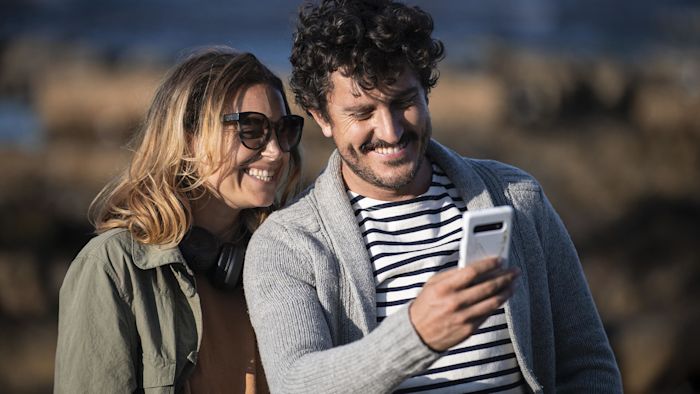 Kvinna och man. Mannen håller i en mobiltelefon.