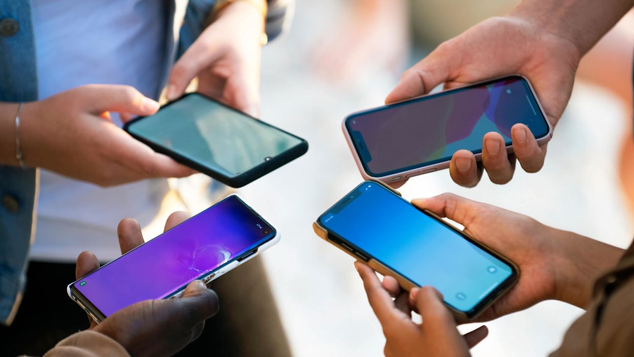 Fyra personer i en ring som håller i olika mobiler.