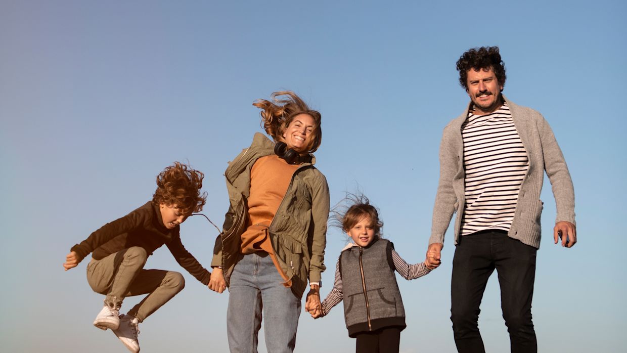 Barnfamilj som hoppar och håller varandra i händerna.