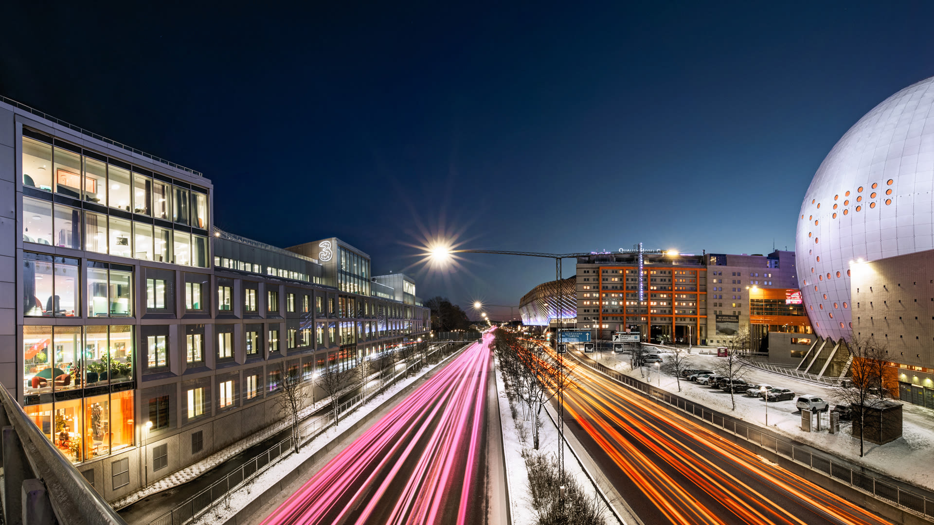 Nattbild över Nynäsvägen med Tres huvudkontor till vänster och Globen till höger.