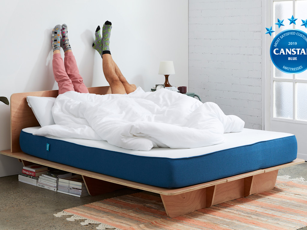 Two people on a Koala bed with legs up the wall.
