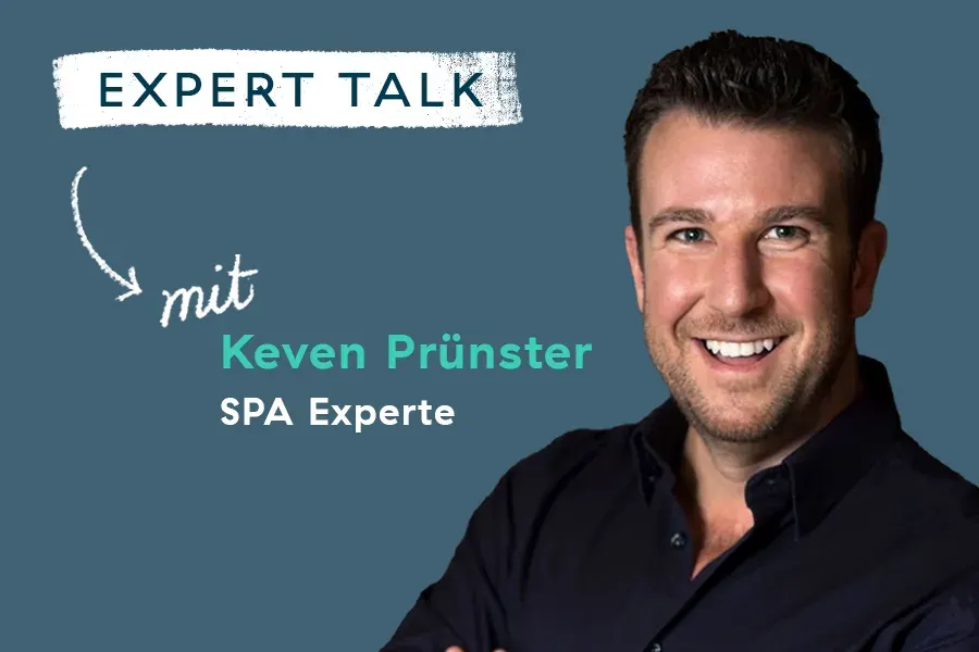 Ein lächelnder Mann mit kurzen dunklen Haaren steht vor einem blauen Hintergrund. Der Text lautet: EXPERT TALK mit Keven Prünster, SPA Experte, mit einem Pfeil, der auf ihn zeigt.