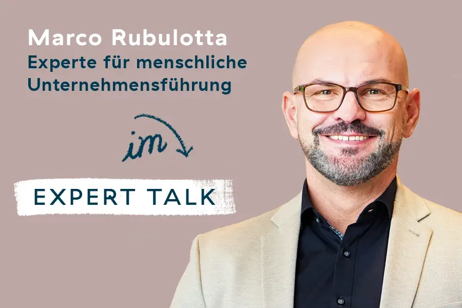 Ein lächelnder kahlköpfiger Mann mit Brille und Bart, der einen beigen Blazer und ein dunkles Hemd trägt, steht neben einem deutschen Text, der ihn als Marco Rubulotta, Experte für Menschenführung, vorstellt, mit der Aufschrift Expert Talk auf dem Bild.