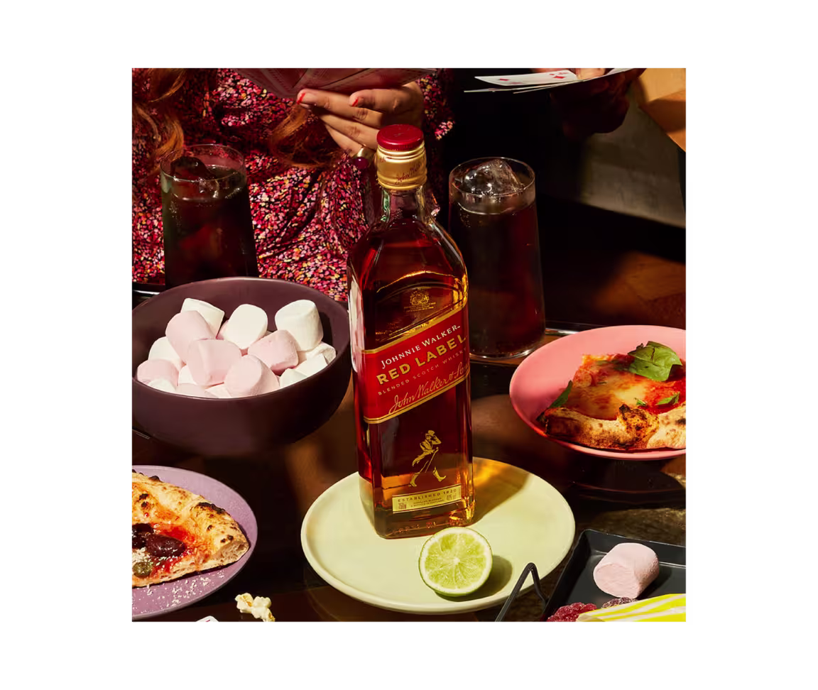Johnnie Walker Red Label Scotch Whisky bottle surrounded by marshmallows and pizza