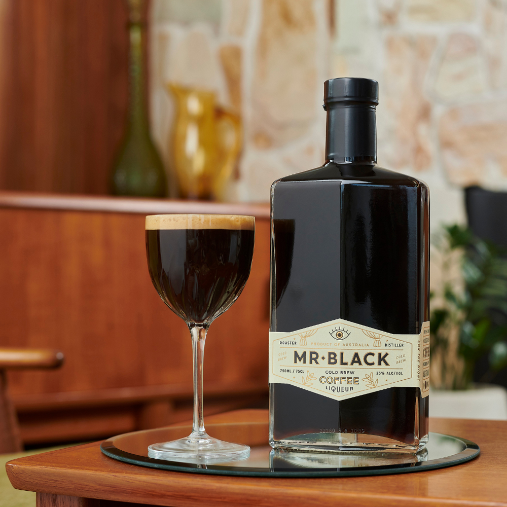 Mr Black Cold Brew Coffee Liqueur bottle next to espresso martini in a glass.