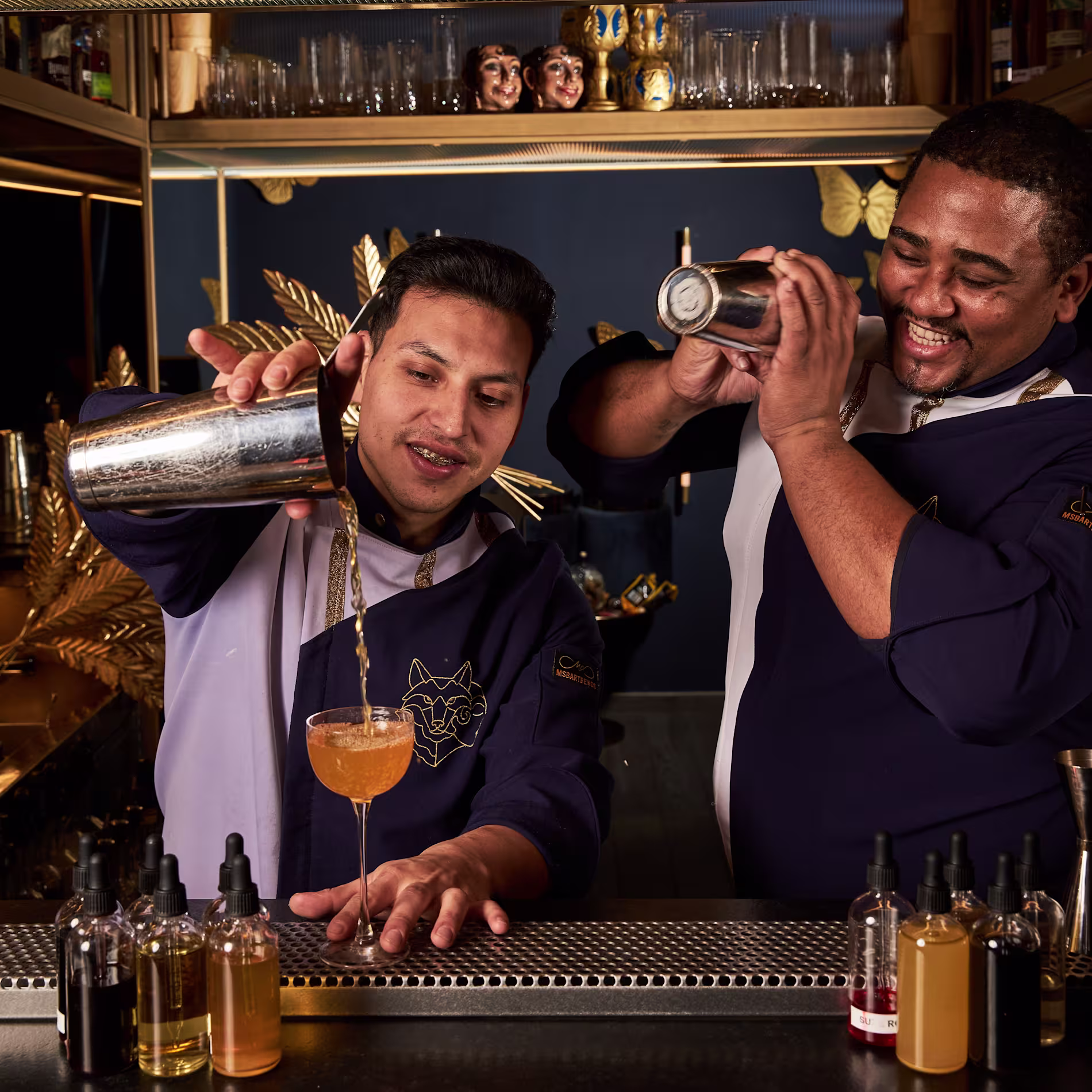 The Bar | Lovo Madrid - Primer plano de un cóctel servido en una copa sobre una roca decorativa, rodeado de un ambiente de vegetación y niebla, evocando un ambiente exótico y sofisticado.