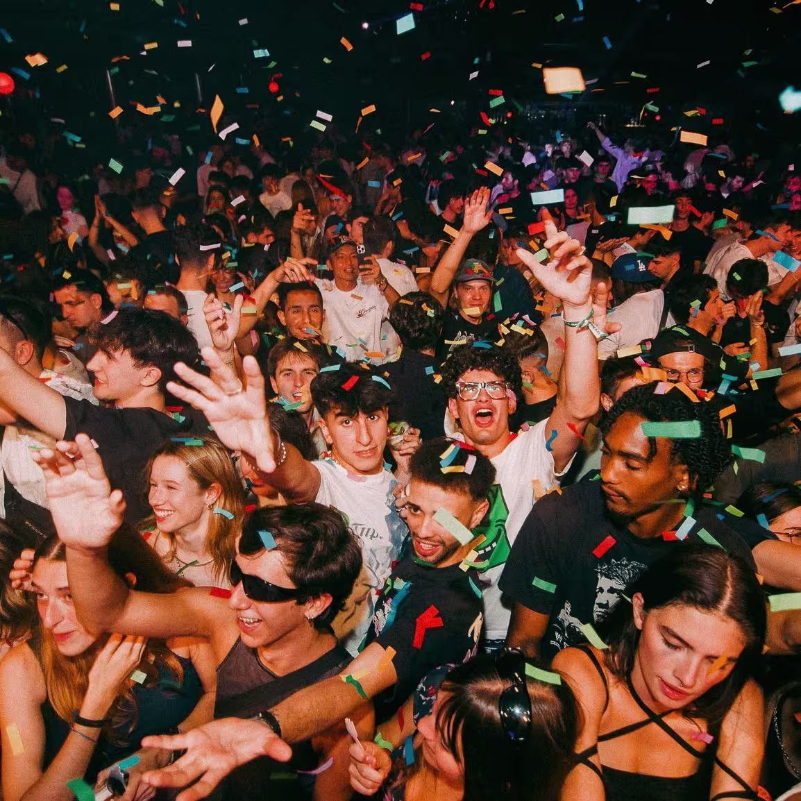 Multitud celebrando con confeti y luces en Sala Apolo, ambiente festivo lleno de energía y diversión.