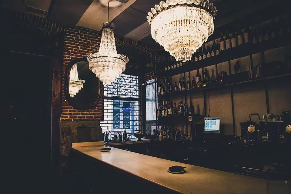Astor destaca con su barra clásica, paredes de ladrillo y majestuosas lámparas de cristal, creando un ambiente vintage y sofisticado.