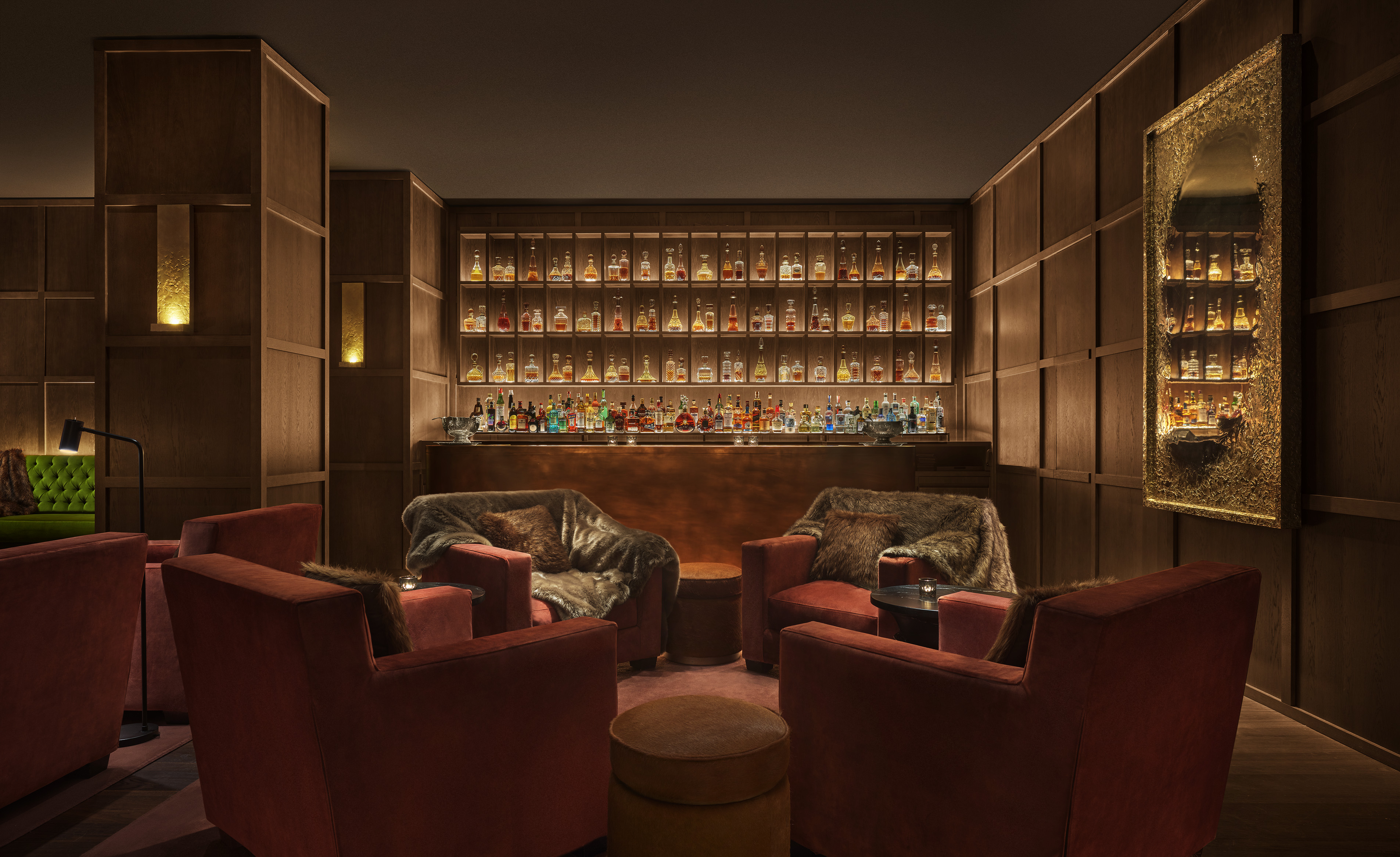 Punch Room, un salón íntimo con sillones de terciopelo, estanterías llenas de botellas y una atmósfera cálida, ideal para cócteles exclusivos.