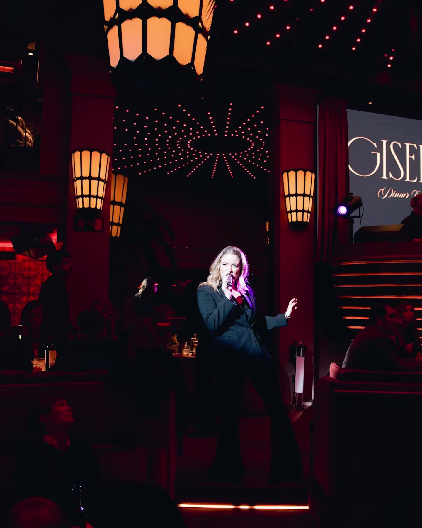 Una cantante en vivo bajo un juego de luces cálidas y modernas en Giselle Dinner Club, creando un ambiente íntimo y sofisticado.