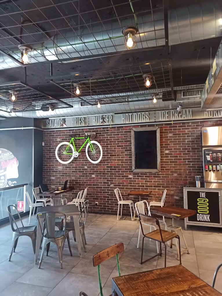 Un ambiente industrial y moderno en The Good Burger, con detalles únicos como una bicicleta decorativa y espacios para relajarse.