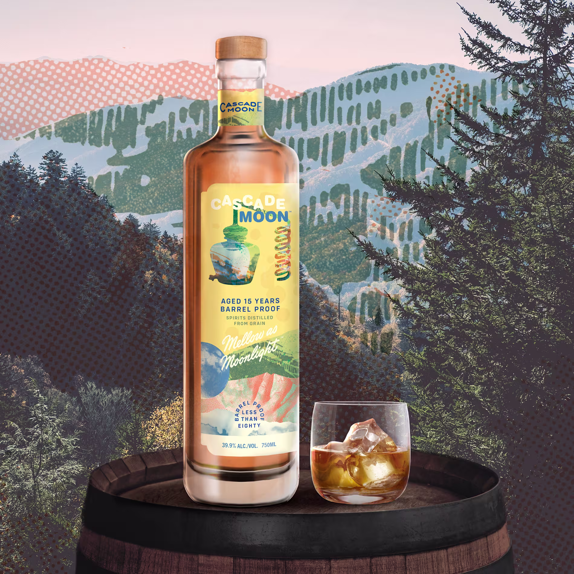 A bottle of Cascade Moon whiskey and a glass with whiskey and ice sit on a wooden barrel, with a scenic forest and mountain landscape in the background.