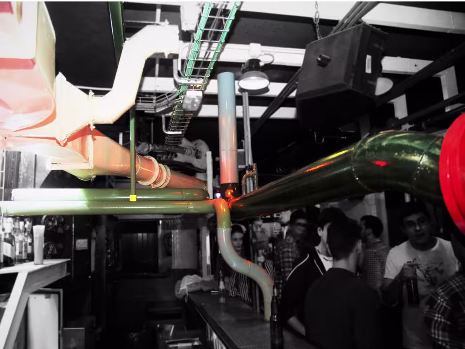 Submarino con tuberías industriales y luces de colores, creando un ambiente único y alternativo para noches de diversión.
