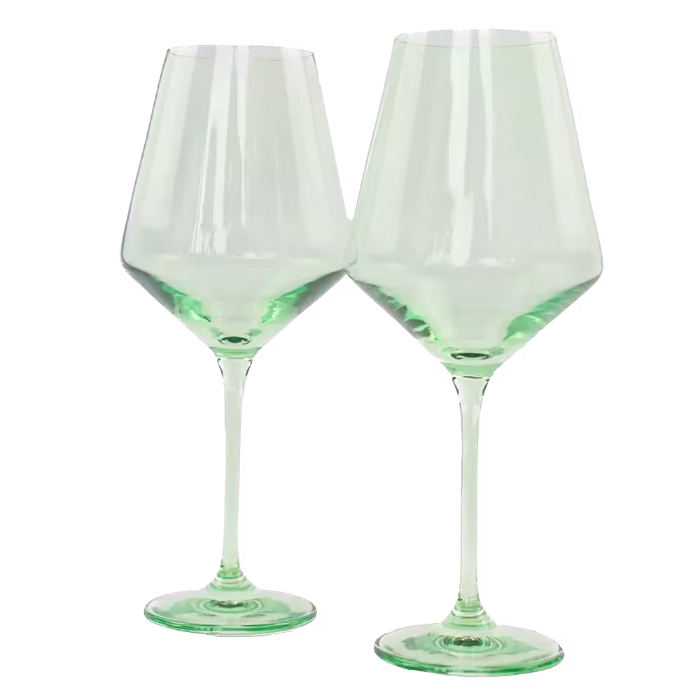 Two clear green-tinted wine glasses with long stems are standing side by side against a black background.